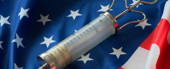 A large medical syringe lies on the American flag