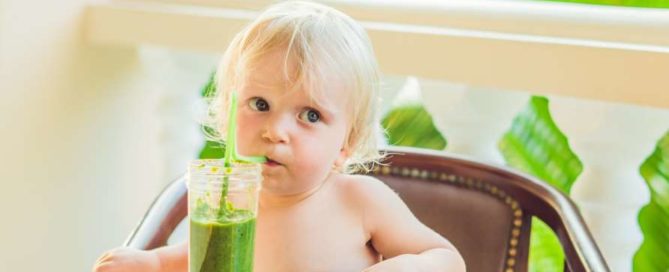 Child boy drinking healthy green vegetable smoothie