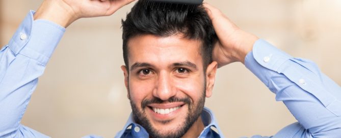 Smiling man brushing fingers through his hair.