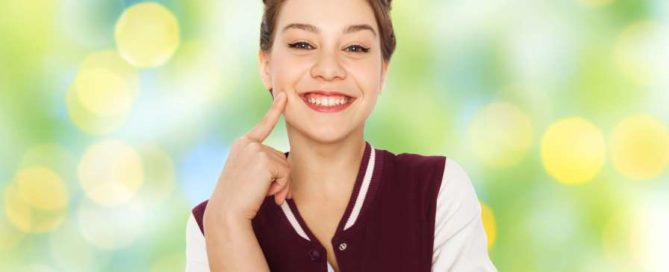 happy smiling pretty teenage girl with eye makeup over green summer holidays lights background