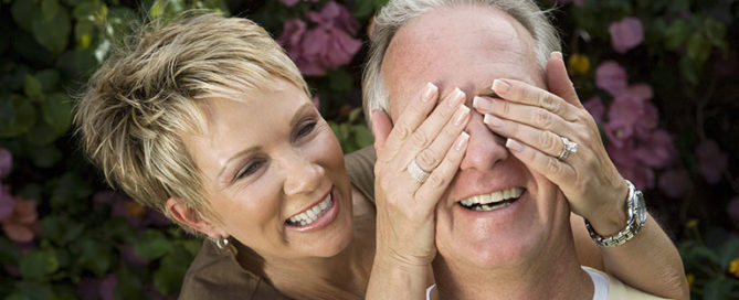 Smiling woman covering the eyes of a smiling man