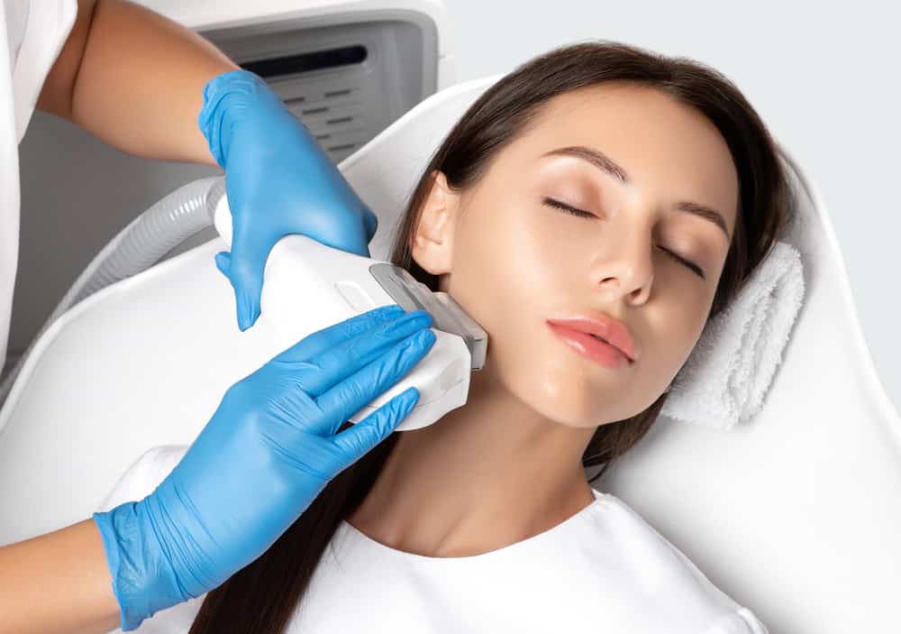 Laser hair removal treatment being performed on woman's jawline