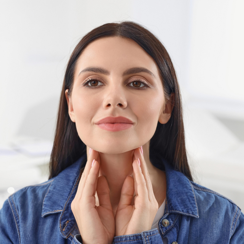 A person lightly touches both sides of their chin while looking straight ahead.