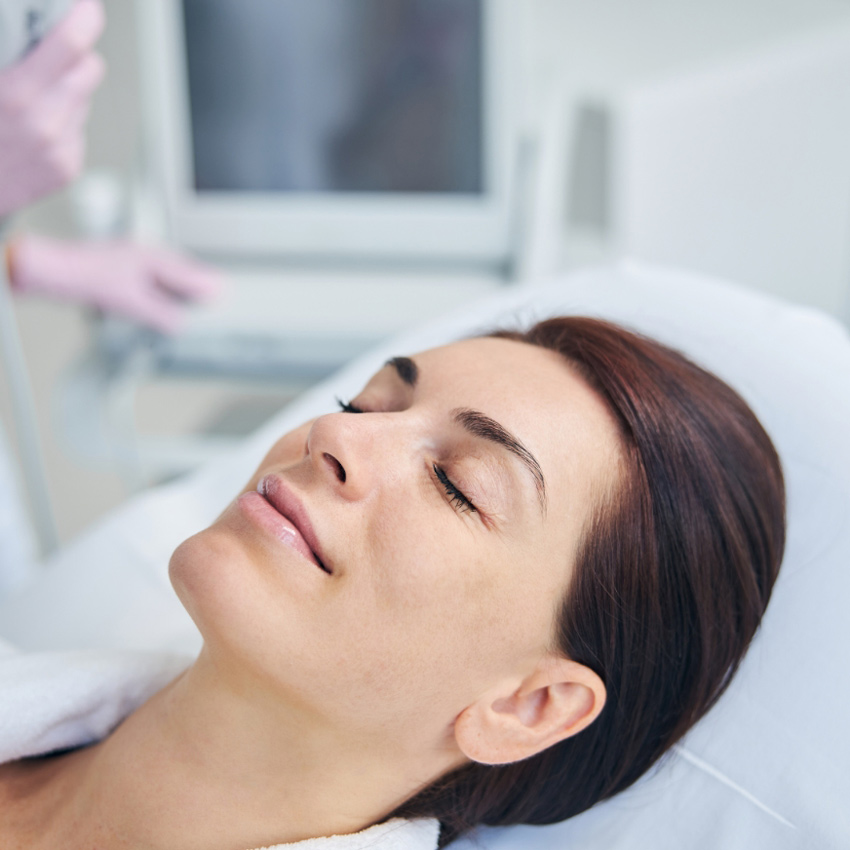 Person lying comfortably with eyes closed during a noninvasive facial procedure.