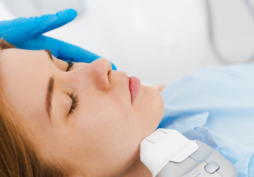 Close-up of a handheld device delivering an energy-based treatment along the jawline.