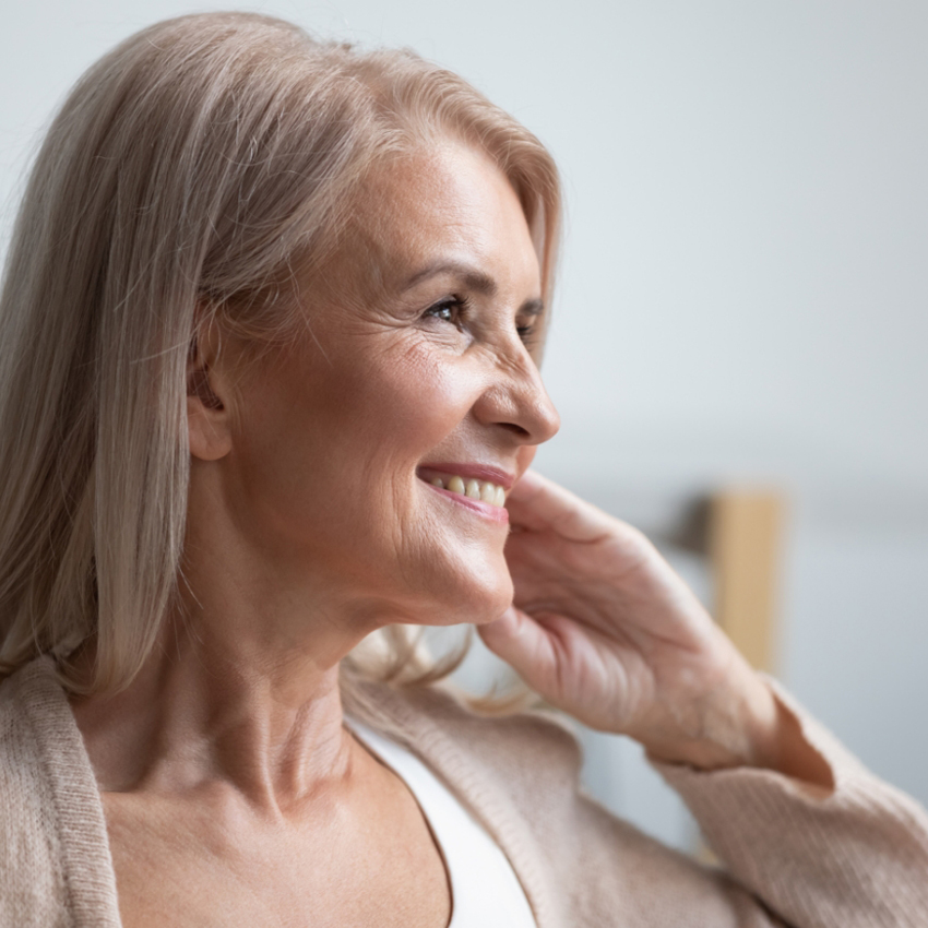 A woman with light blonde hair smiles gently while looking off to the side.