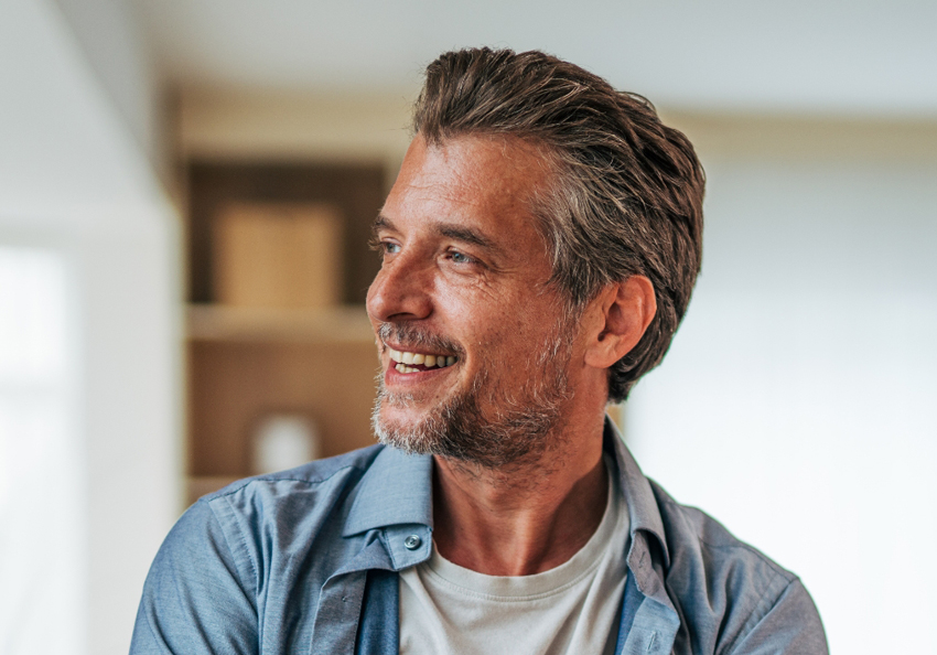 A man with short salt-and-pepper hair looks off to the side with a relaxed smile.