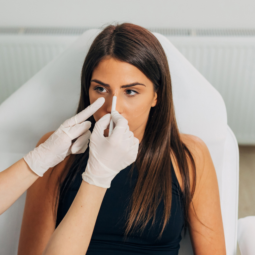 A gloved clinician points to the bridge of a person’s nose during an assessment.