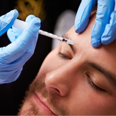 man gets cosmetic botox injected into eyebrow showing botox uses cosmetic
